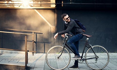A man is sitting on his bike on a sidewalk 